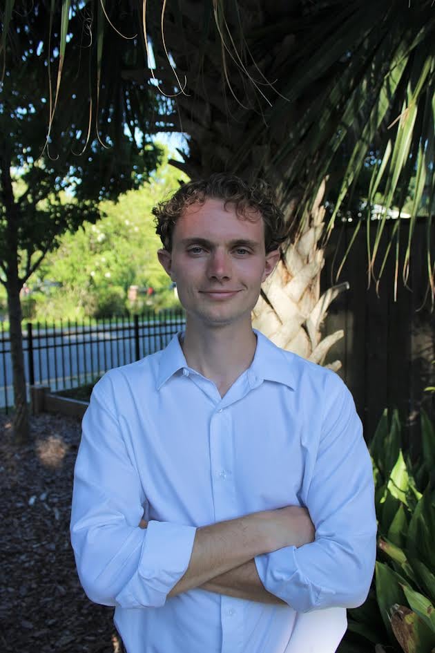 Owen Gates, founder of Hamayim Health, standing outdoors under palm trees